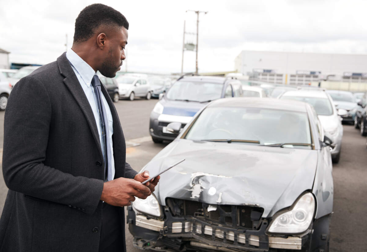 Man looking at damaged car for scrap